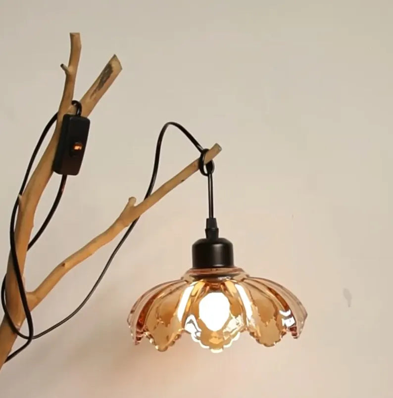 Applique in vetro ambrato accesa con supporto a ramo su parete chiara