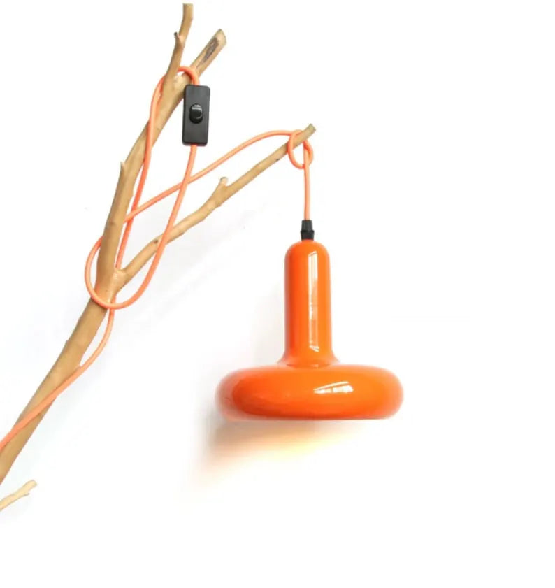 Lampada a sospensione arancione con cavo a vista fissata a un ramo decorativo