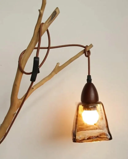 Lampada a sospensione in vetro ambrato appesa a un ramo di legno naturale