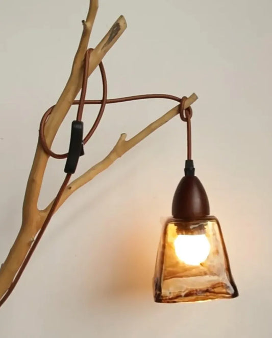 Lampada a sospensione in vetro ambrato appesa a un ramo di legno naturale