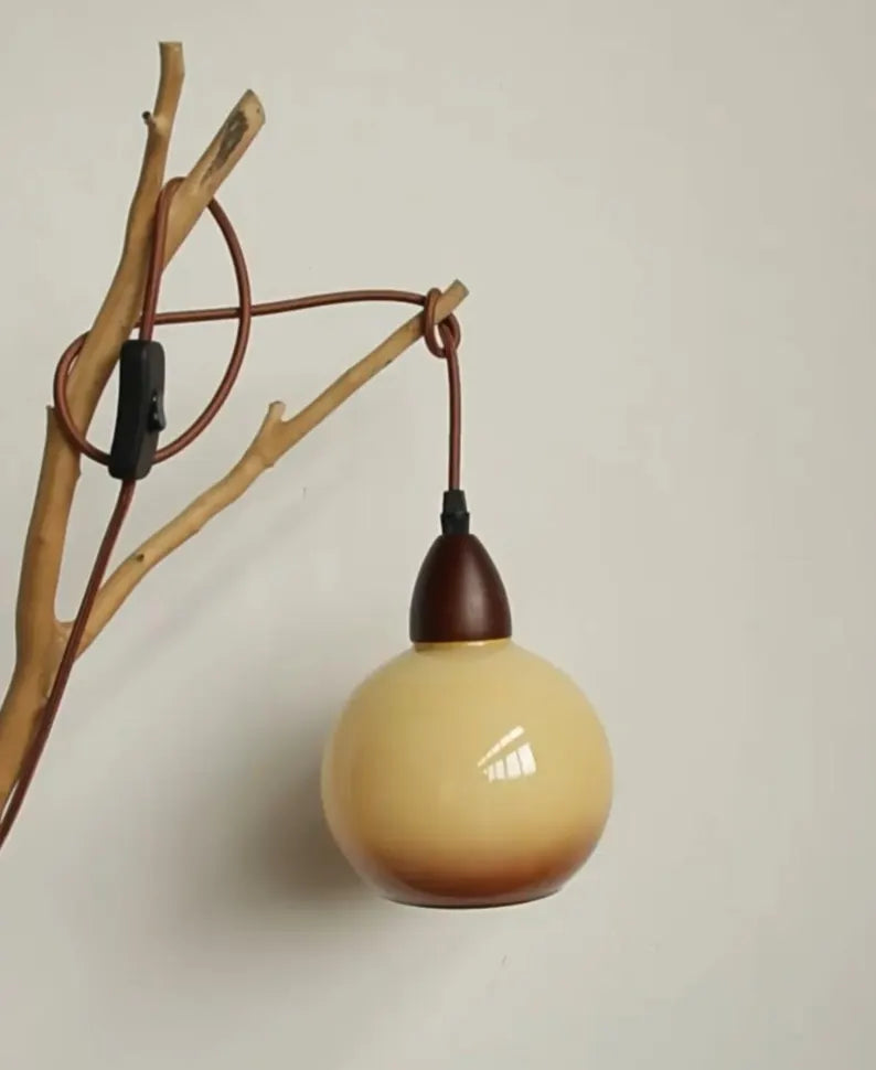 Lampada in vetro ambrato sospesa a ramo decorativo su parete