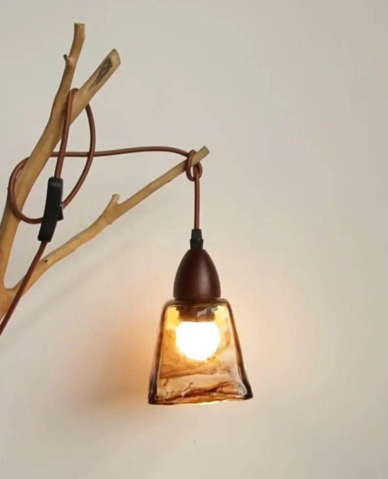Lampada in vetro artistico appesa a ramo decorativo su parete chiara