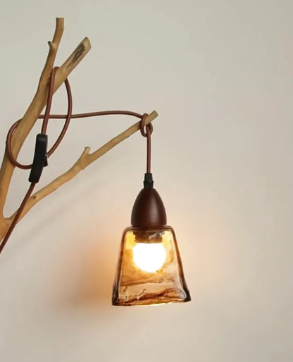 Lampada in vetro artistico appesa a ramo decorativo su parete chiara
