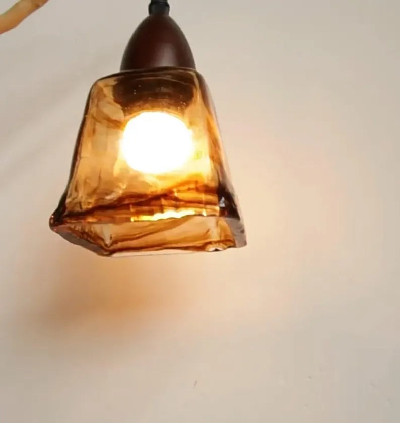 Lampada pendente in vetro ambrato accesa su sfondo chiaro