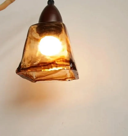 Lampada pendente in vetro ambrato accesa su sfondo chiaro